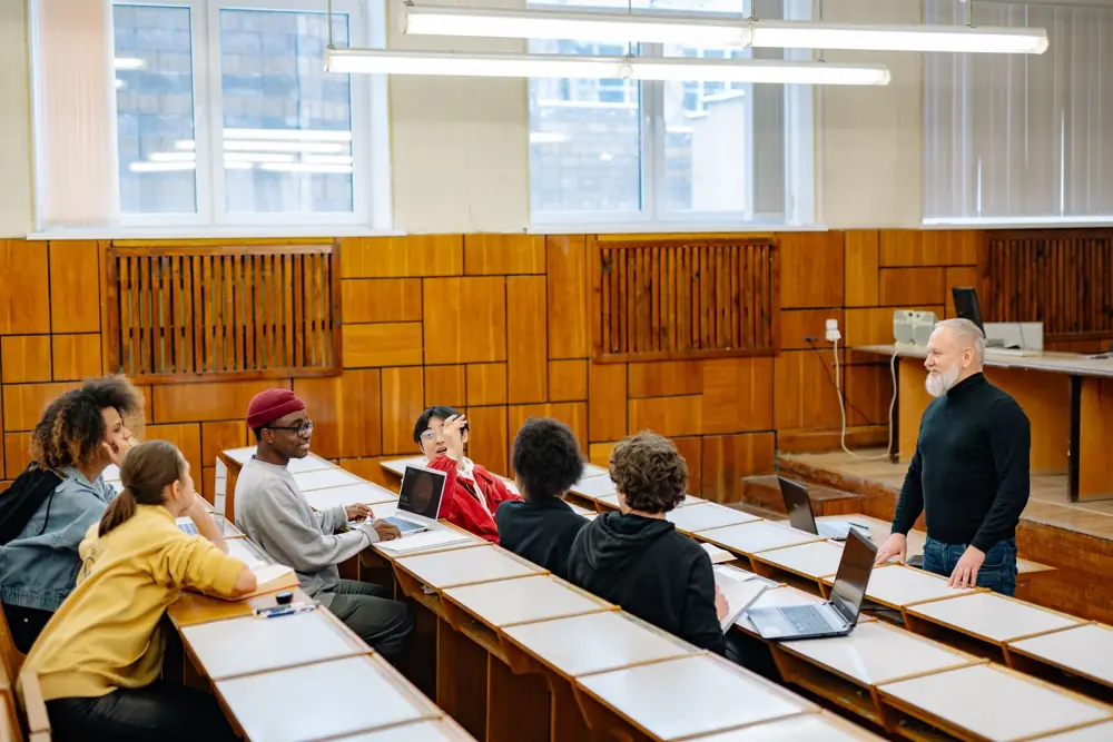 A professor talking with a diverse group of students in a lecture hall